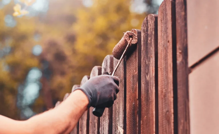 fence being painted with a roller brush